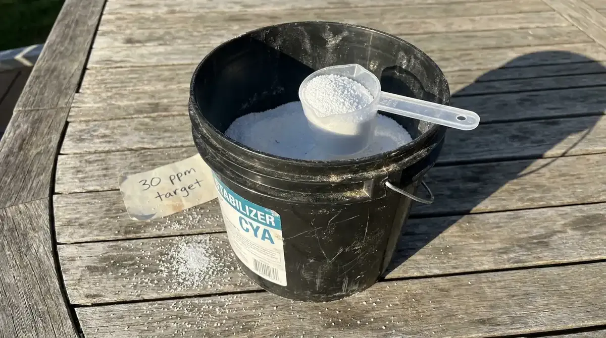 cyanuric acid stabilizer granules being scooped from black container