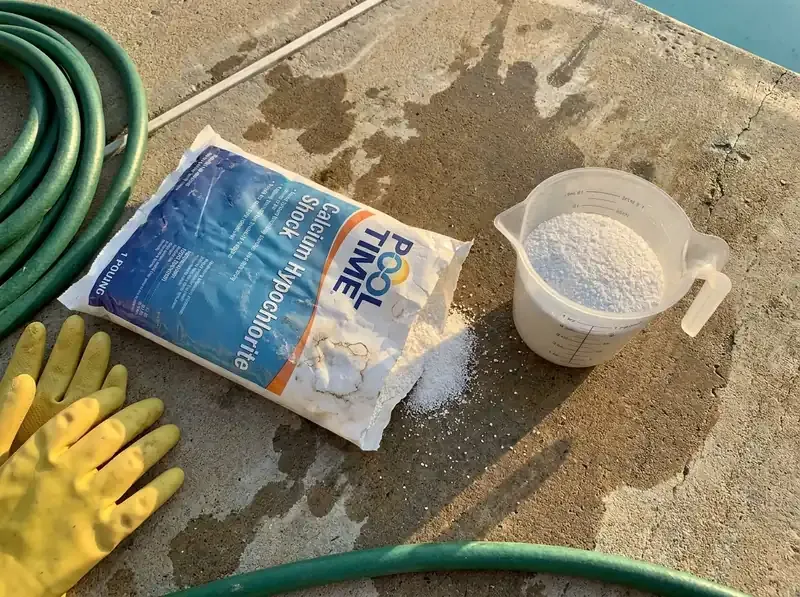 opened bag of calcium hypochlorite pool shock with measuring cup of granules beside it